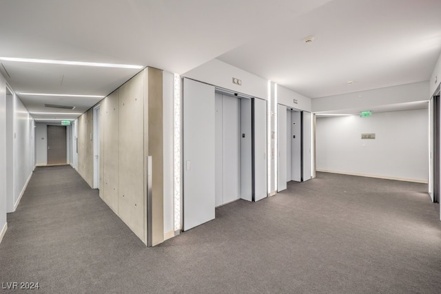 hallway featuring dark colored carpet and elevator