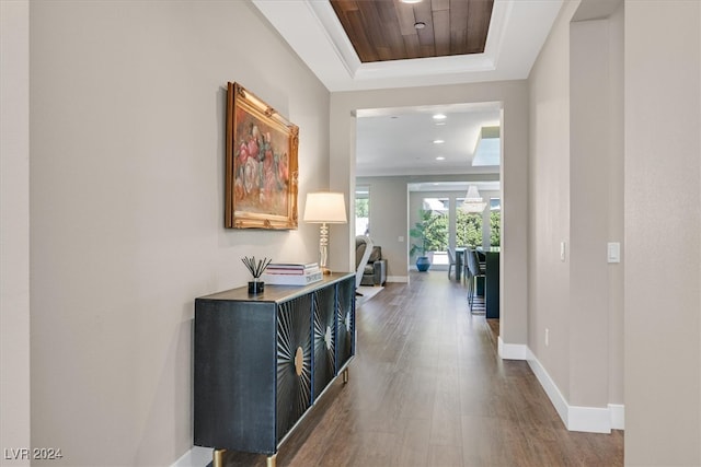 corridor with a tray ceiling and hardwood / wood-style floors