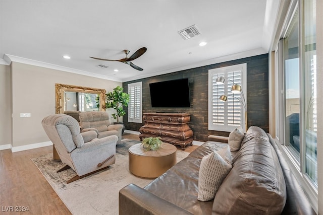 living room with light hardwood / wood-style floors, ornamental molding, and ceiling fan