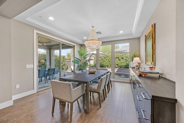 dining area featuring a raised ceiling, an inviting chandelier, and light hardwood / wood-style flooring