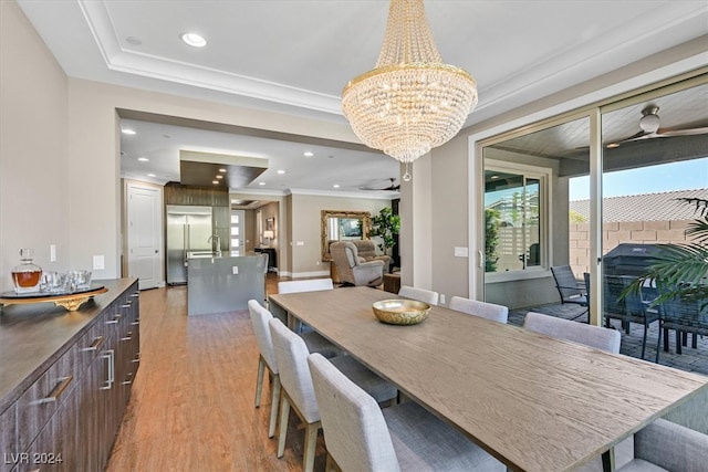 dining space featuring light wood-type flooring, ceiling fan with notable chandelier, and ornamental molding