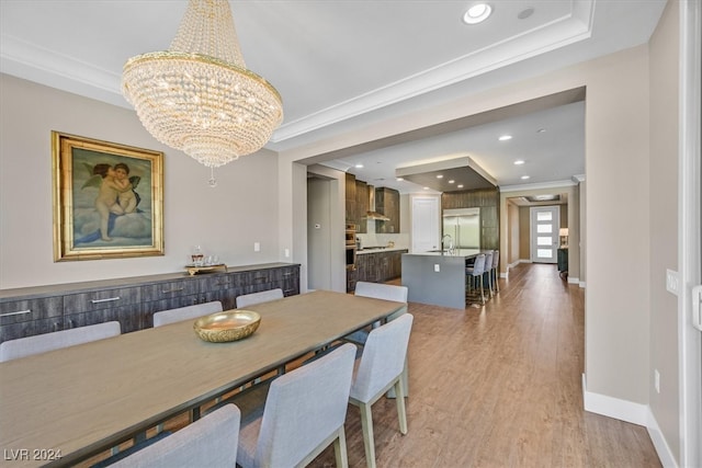 dining room with crown molding, light hardwood / wood-style floors, sink, and a notable chandelier