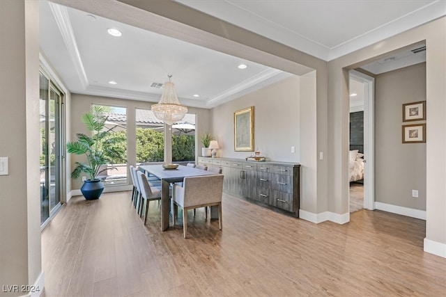 dining room featuring ornamental molding, an inviting chandelier, and light hardwood / wood-style flooring