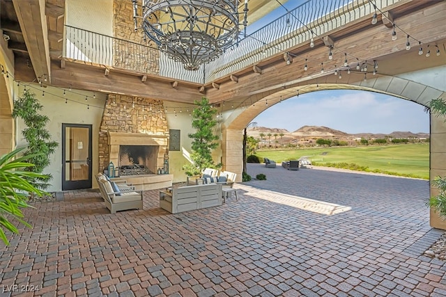 view of patio featuring a balcony and an outdoor stone fireplace