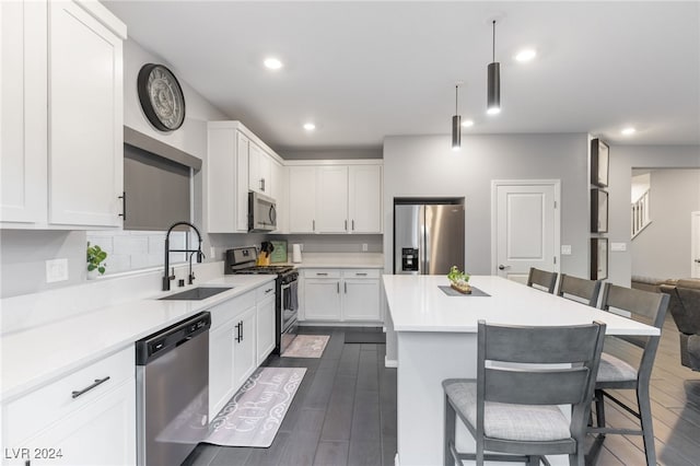 kitchen with appliances with stainless steel finishes, a breakfast bar area, sink, and dark hardwood / wood-style floors