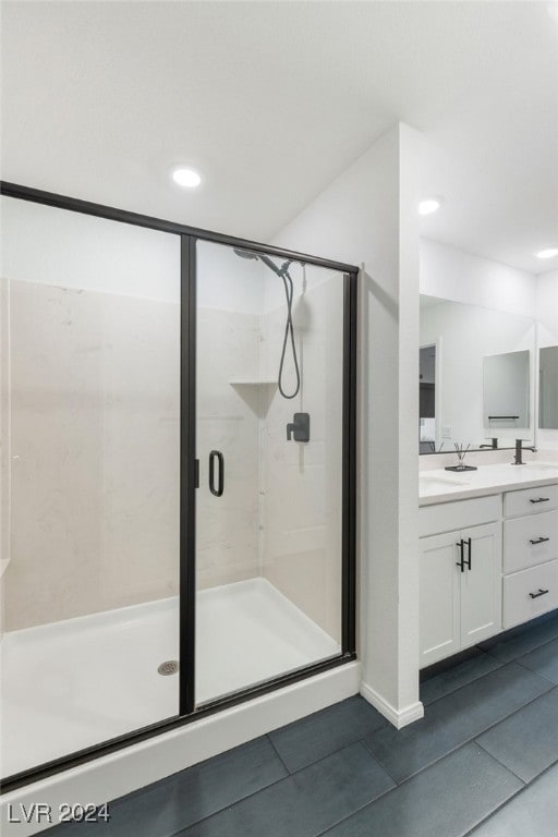 bathroom with walk in shower, vanity, and tile patterned flooring