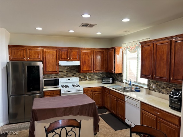 kitchen with appliances with stainless steel finishes, sink, tasteful backsplash, and a center island