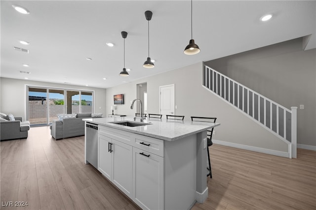 kitchen with sink, stainless steel dishwasher, decorative light fixtures, white cabinetry, and light stone countertops