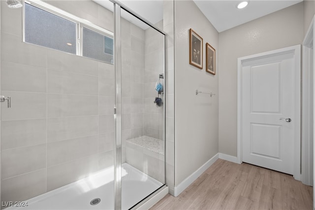 bathroom with hardwood / wood-style flooring and a shower with shower door