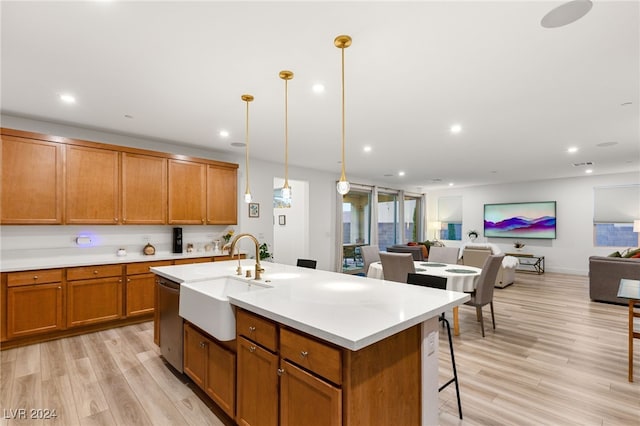 kitchen featuring hanging light fixtures, light hardwood / wood-style floors, an island with sink, dishwasher, and sink