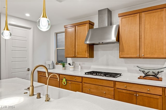 kitchen featuring stainless steel gas stovetop, wall chimney exhaust hood, and decorative light fixtures