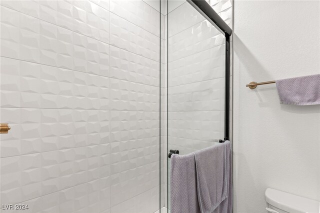 bathroom with a shower with shower door and toilet