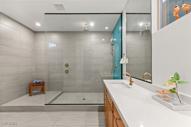 bathroom with a tile shower, tile patterned flooring, and vanity