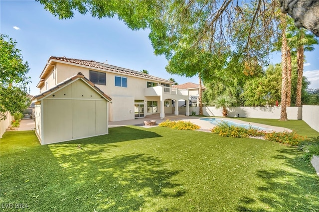 back of property with a balcony, a yard, a fenced in pool, and a patio area