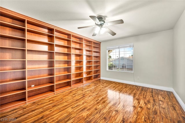 empty room featuring hardwood / wood-style floors, built in shelves, and ceiling fan