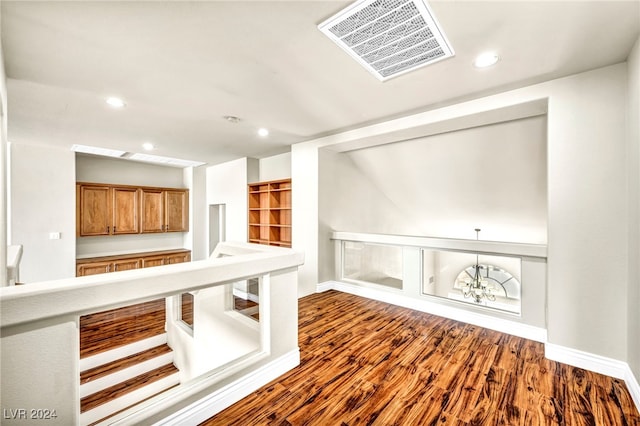 interior space featuring built in shelves, wood-type flooring, and a chandelier