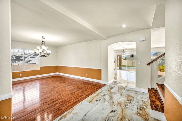 unfurnished room with a notable chandelier, hardwood / wood-style flooring, and a healthy amount of sunlight