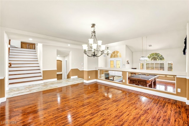 unfurnished dining area featuring a notable chandelier, wood-type flooring, and vaulted ceiling