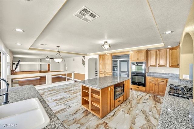 kitchen featuring sink, black appliances, a raised ceiling, and a kitchen island