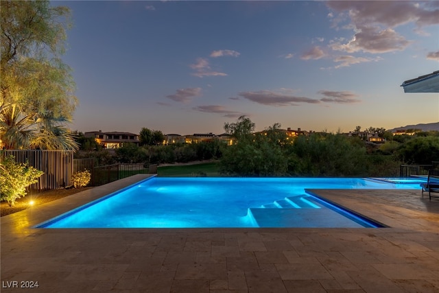 pool at dusk with a patio area