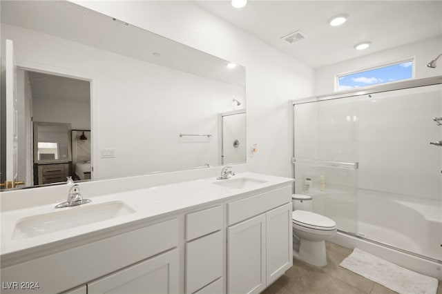 bathroom featuring tile patterned flooring, a shower with door, toilet, and vanity