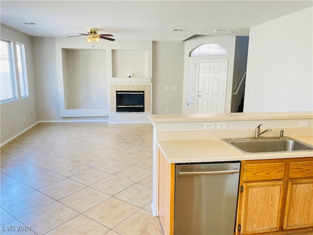 kitchen with a fireplace, ceiling fan, sink, light tile patterned floors, and dishwasher