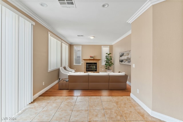 unfurnished living room featuring ornamental molding, a tiled fireplace, and light tile patterned floors