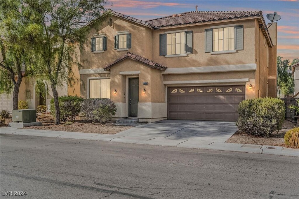 1838 Shining Elm Ct, North Las Vegas, NV 89031 - view of front facade featuring a tiled roof, concrete driveway, stucco siding, and a garage