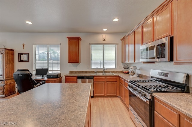 kitchen with appliances with stainless steel finishes, light wood-type flooring, and sink