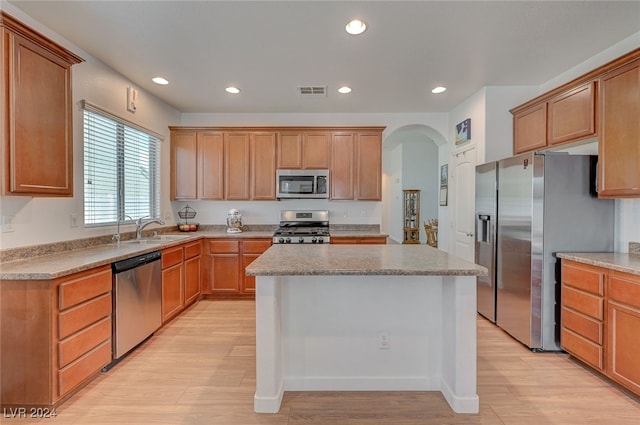 kitchen featuring appliances with stainless steel finishes, light hardwood / wood-style floors, a center island, and sink