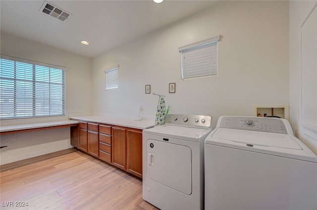 washroom featuring light hardwood / wood-style flooring, cabinets, and separate washer and dryer