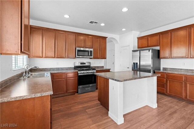 kitchen featuring dark wood-type flooring, stainless steel appliances, a center island, and sink