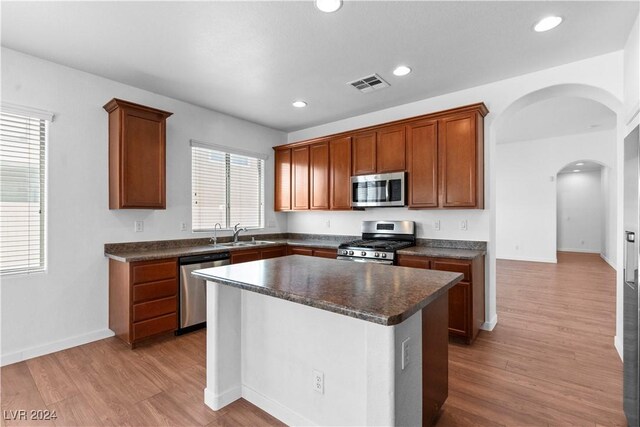 kitchen with stainless steel appliances, a center island, sink, and light wood-type flooring