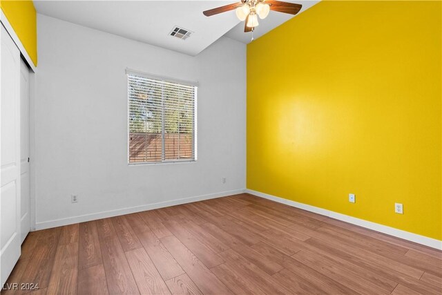 empty room with hardwood / wood-style flooring, lofted ceiling, and ceiling fan