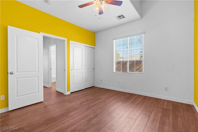 unfurnished bedroom featuring hardwood / wood-style flooring, ceiling fan, and a closet