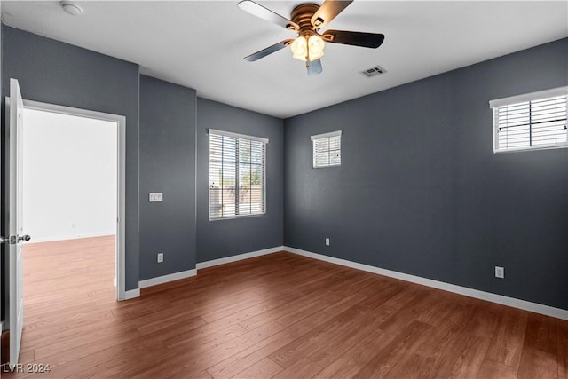 spare room featuring visible vents, baseboards, ceiling fan, and wood finished floors