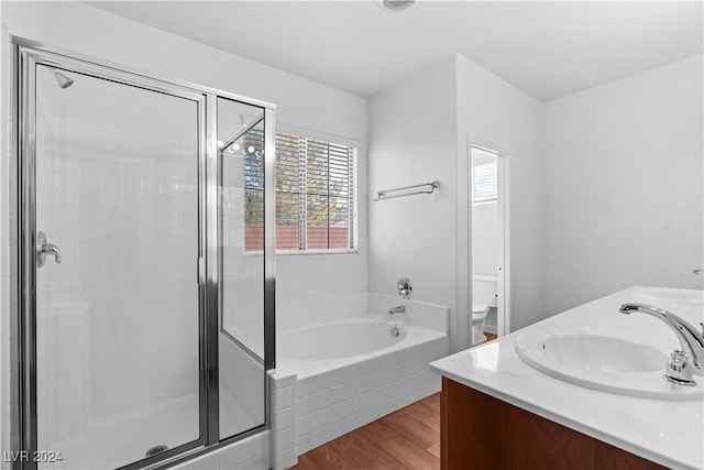 full bath featuring wood finished floors, toilet, a stall shower, a sink, and a bath