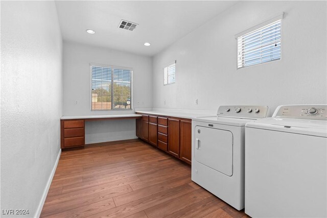 washroom featuring cabinets, washing machine and clothes dryer, and light wood-type flooring