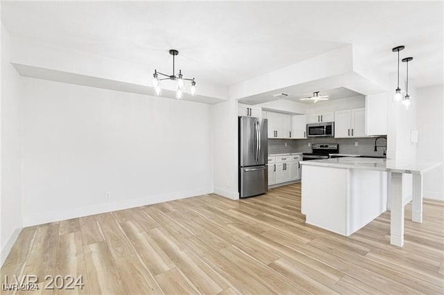 kitchen featuring tasteful backsplash, stainless steel appliances, white cabinetry, pendant lighting, and a breakfast bar