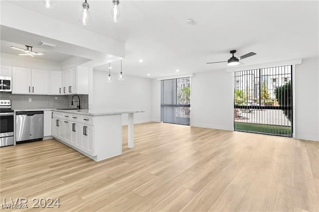 kitchen with white cabinets, light hardwood / wood-style floors, appliances with stainless steel finishes, and sink