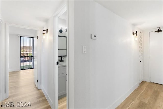 hallway with light wood-type flooring and sink