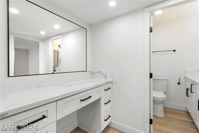 bathroom with hardwood / wood-style floors, vanity, and toilet