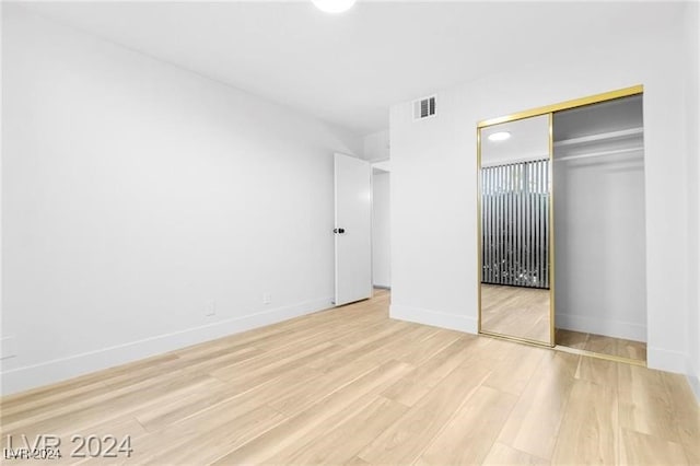 unfurnished bedroom with a closet and light hardwood / wood-style floors