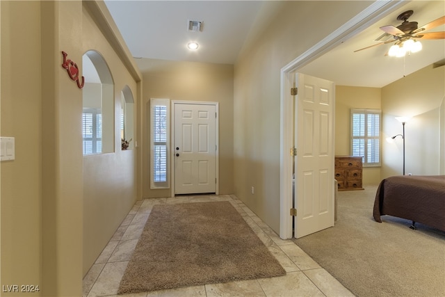 foyer entrance with ceiling fan and light carpet