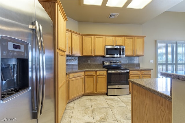 kitchen featuring decorative backsplash, vaulted ceiling, appliances with stainless steel finishes, and light tile patterned floors