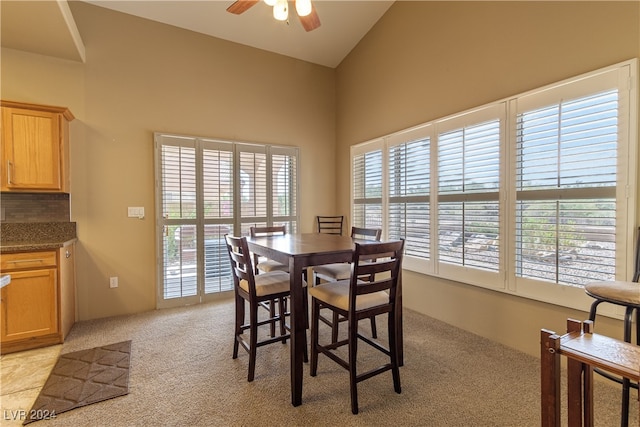 dining area with ceiling fan, light carpet, and vaulted ceiling