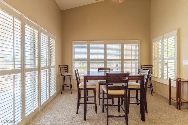 dining area with light colored carpet and high vaulted ceiling