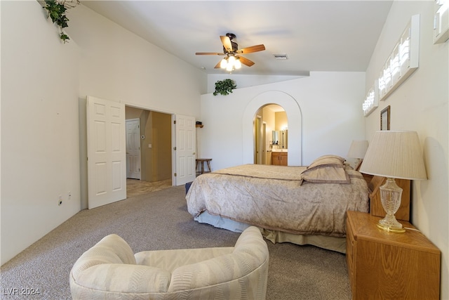 carpeted bedroom featuring ceiling fan, lofted ceiling, and ensuite bath