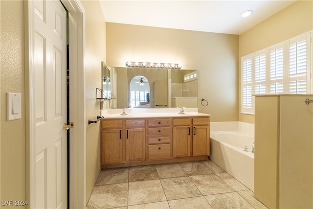 bathroom featuring tiled tub and vanity