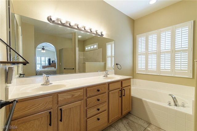 bathroom featuring tiled tub, vanity, ceiling fan, and tile patterned flooring